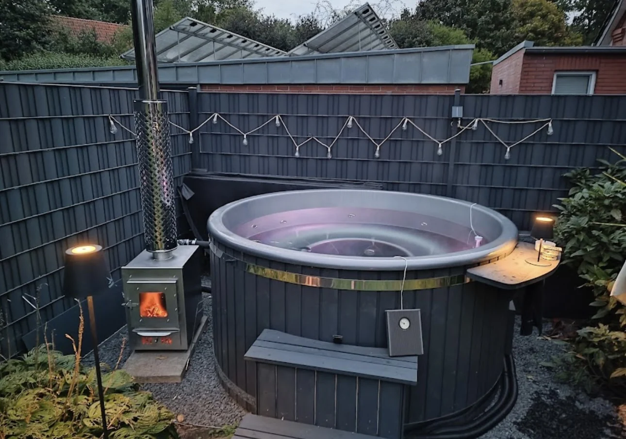 Befüllter Hot Tub mit brennendem Holzofen im Garten