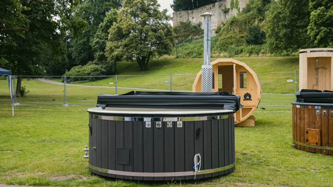 Mehrere Hot Tubs und eine Fasssauna auf einer Wiese